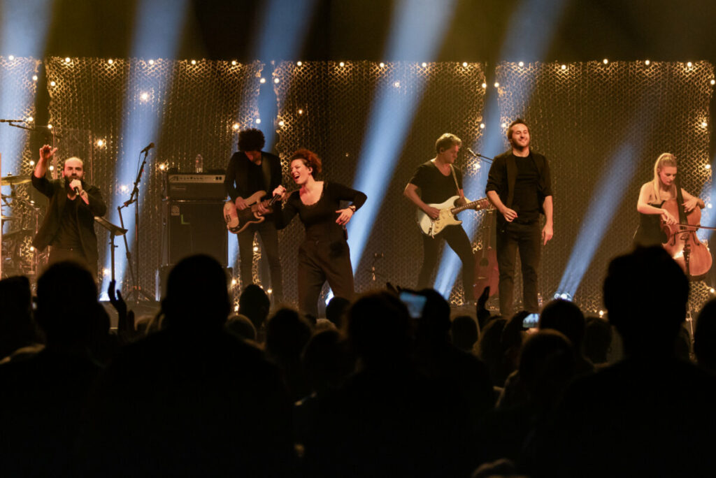 Concert en direct avec des artistes sur scène, chanteurs et musiciens captivant le public.