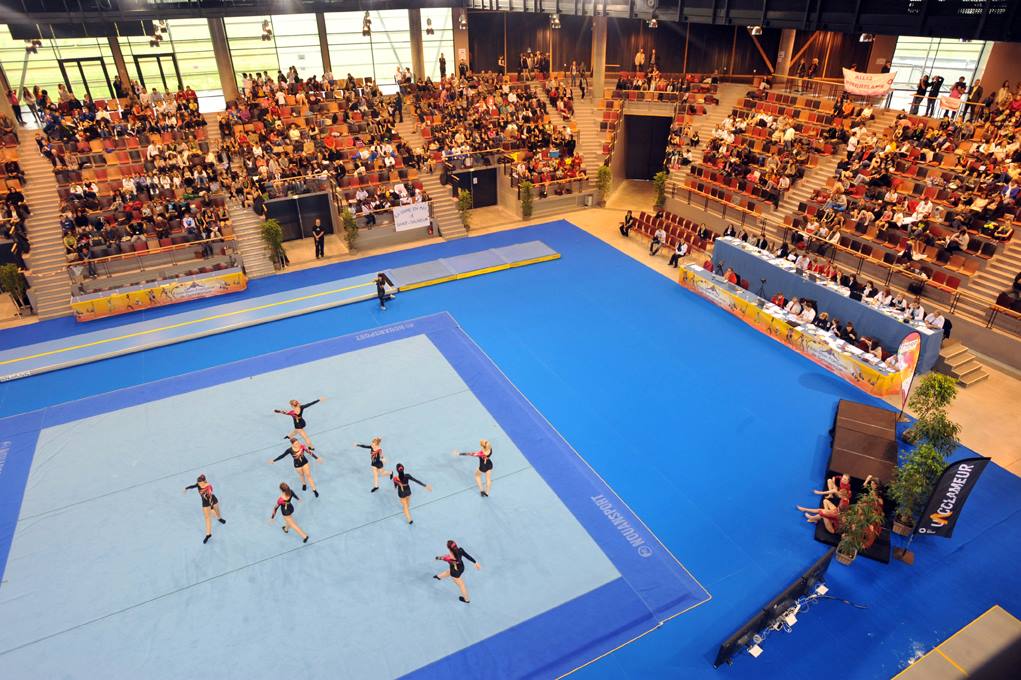 Compétition de gymnastique artistique avec des athlètes performants devant un public nombreux.