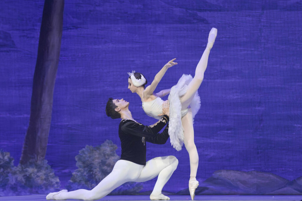 Danseurs de ballet exécutant une pose élégante sur scène, illustrant la grâce et la passion de leur performance.