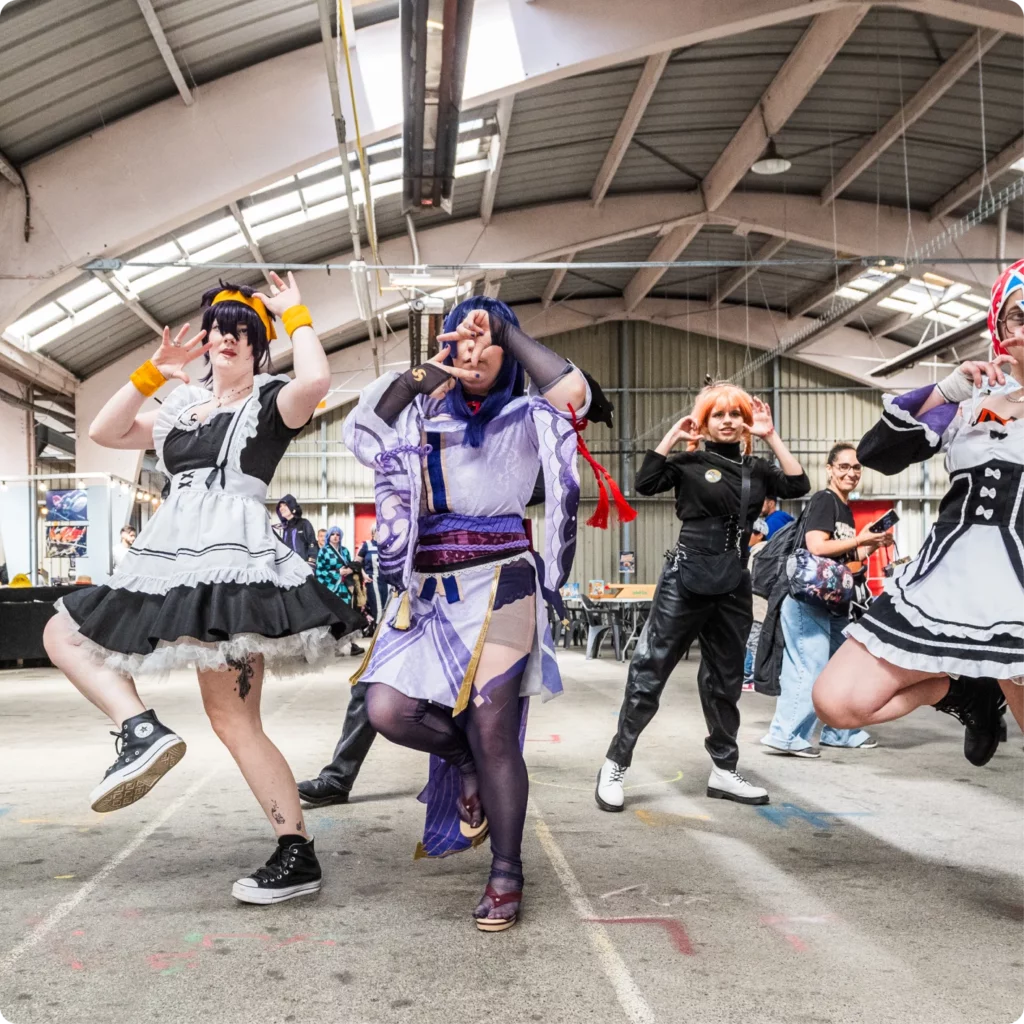 Participants dans un cosplay dansent lors d'un événement, exprimant enthousiasme et créativité.