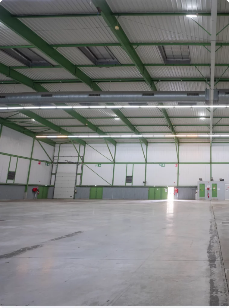 Espace de travail intérieur spacieux avec plafond lumineux et accès aux portes.