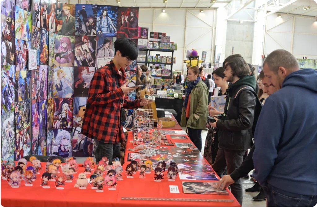Bazar d'objets de collection avec des figurines et des affiches, des visiteurs explorant les stands.