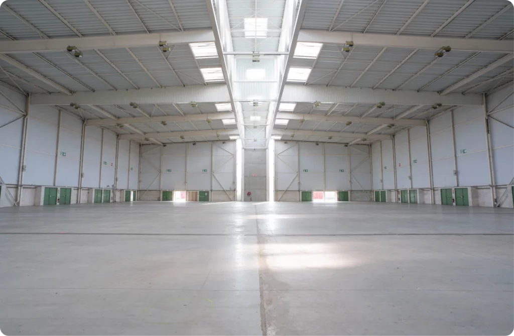 Espace intérieur vaste et vide avec des portes vertes et un plafond lumineux.