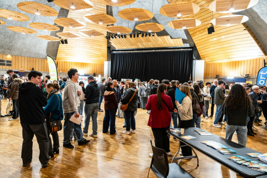 Un groupe de personnes interagissant lors d'un événement dans une salle spacieuse avec un plafond en bois.