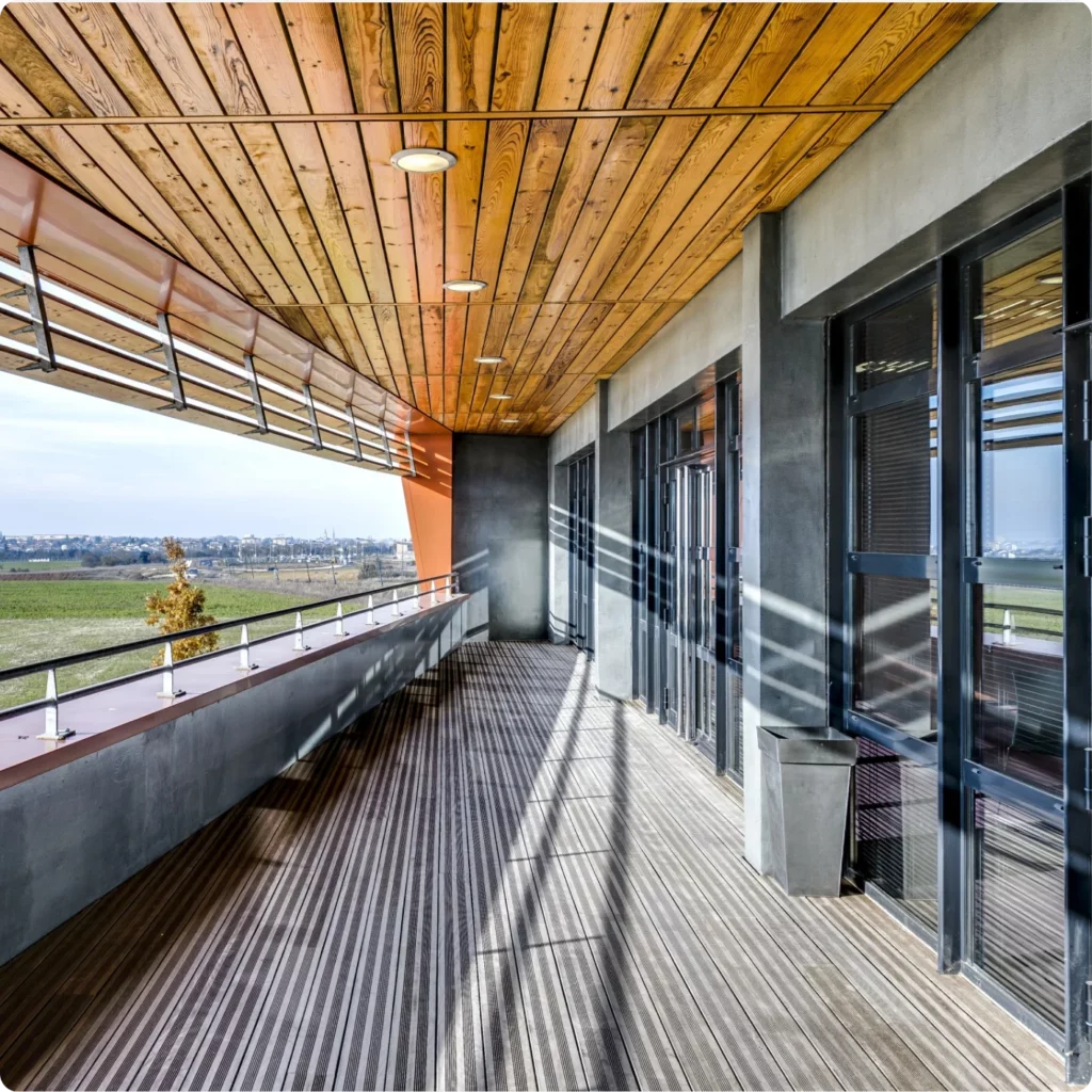 Vue d'une terrasse moderne avec un grand espace, des baies vitrées et un paysage verdoyant en arrière-plan.