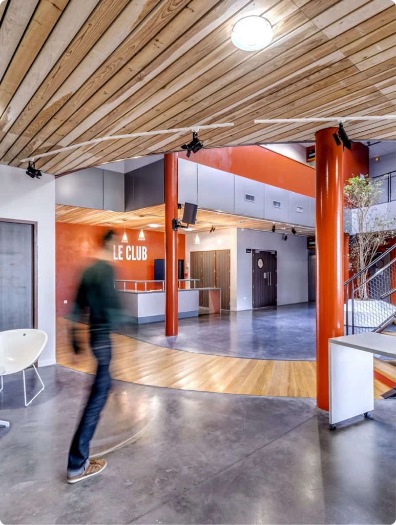 Espace intérieur moderne avec un homme en mouvement vers le bar d'accueil LE CLUB.