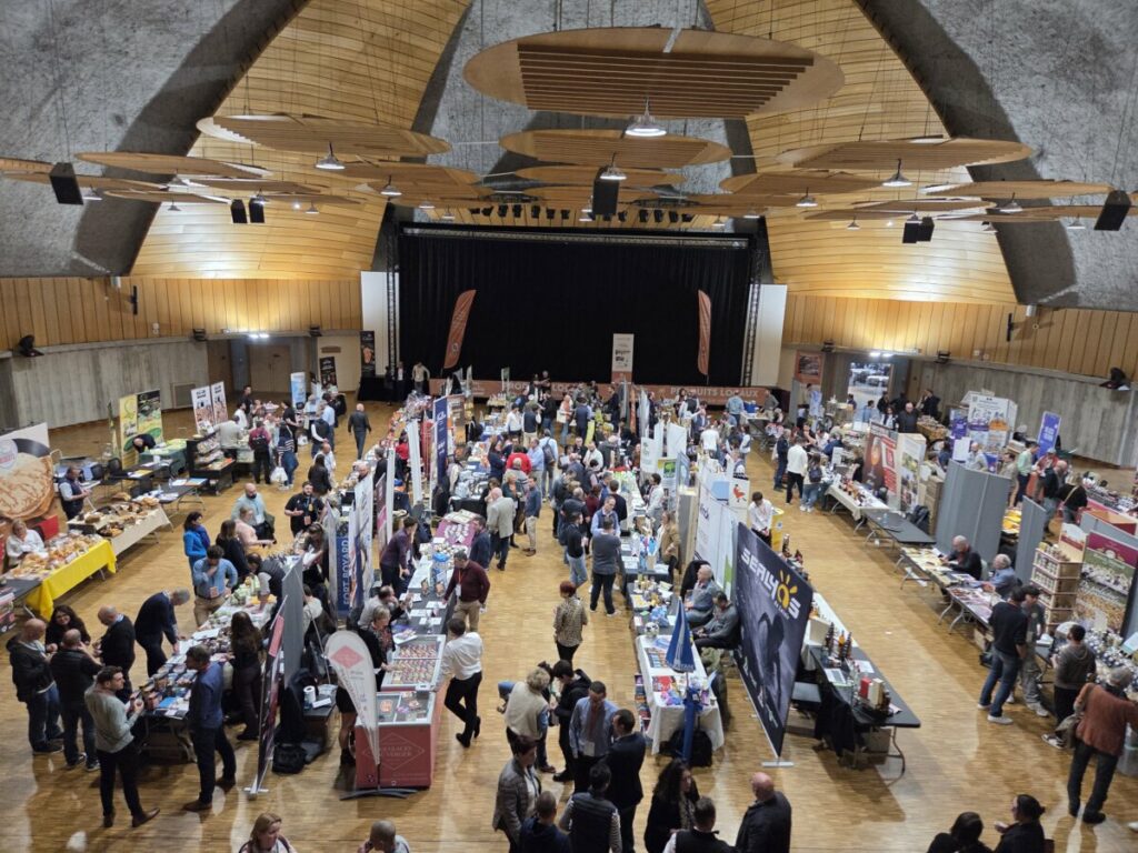 Foule animée à un événement, avec des stands et des participants interagissant ensemble.