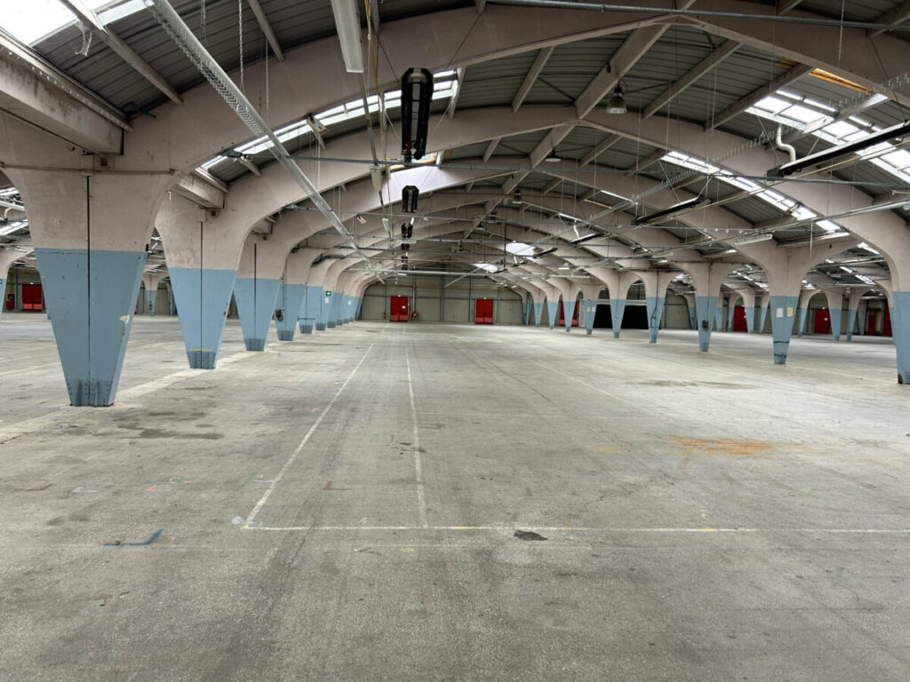 Grand espace intérieur avec arches et portes rouges, prêt pour un événement ou une exposition.